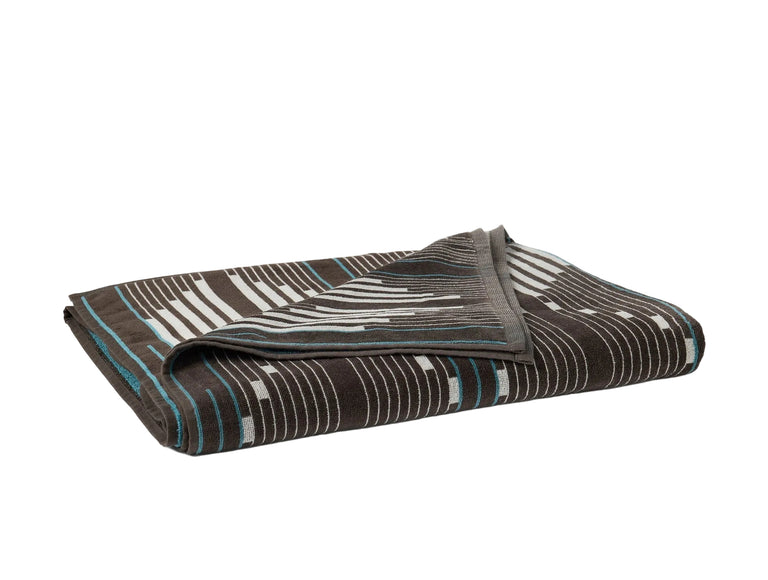 MORELIA ORGANIC BEACH TOWEL | Folded black beach towel with graphic pattern